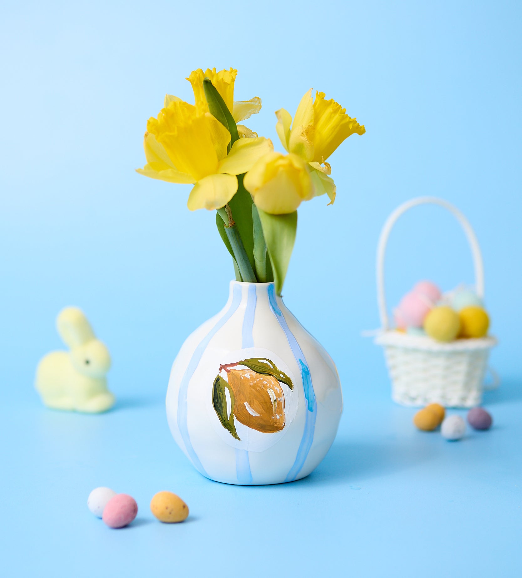 Home pottery and candle making kit with pastel paints, tools, and cactus-shaped candle holder on pink background.