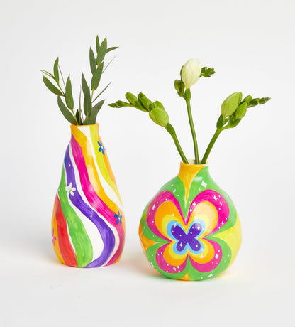 Gift box labeled "Date Night Candle Kit" with gold ribbon, cartoon design, held above pink tablecloth with pink flowers.